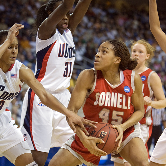 A Cornell basketball player surrounded by UConn defenders protects the basketball.
