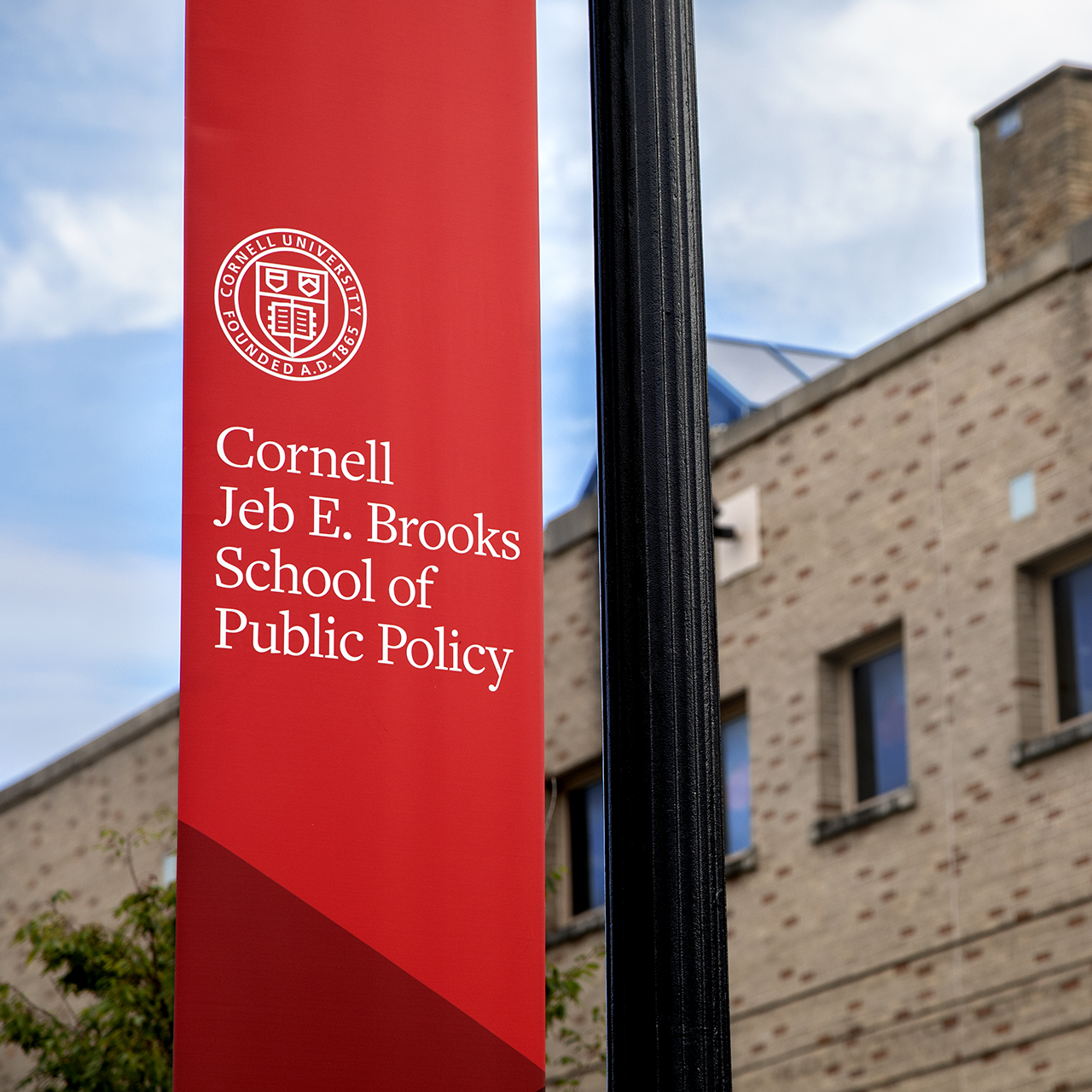 Red lamppost banner for the Jeb E. Brooks School of Public Policy.