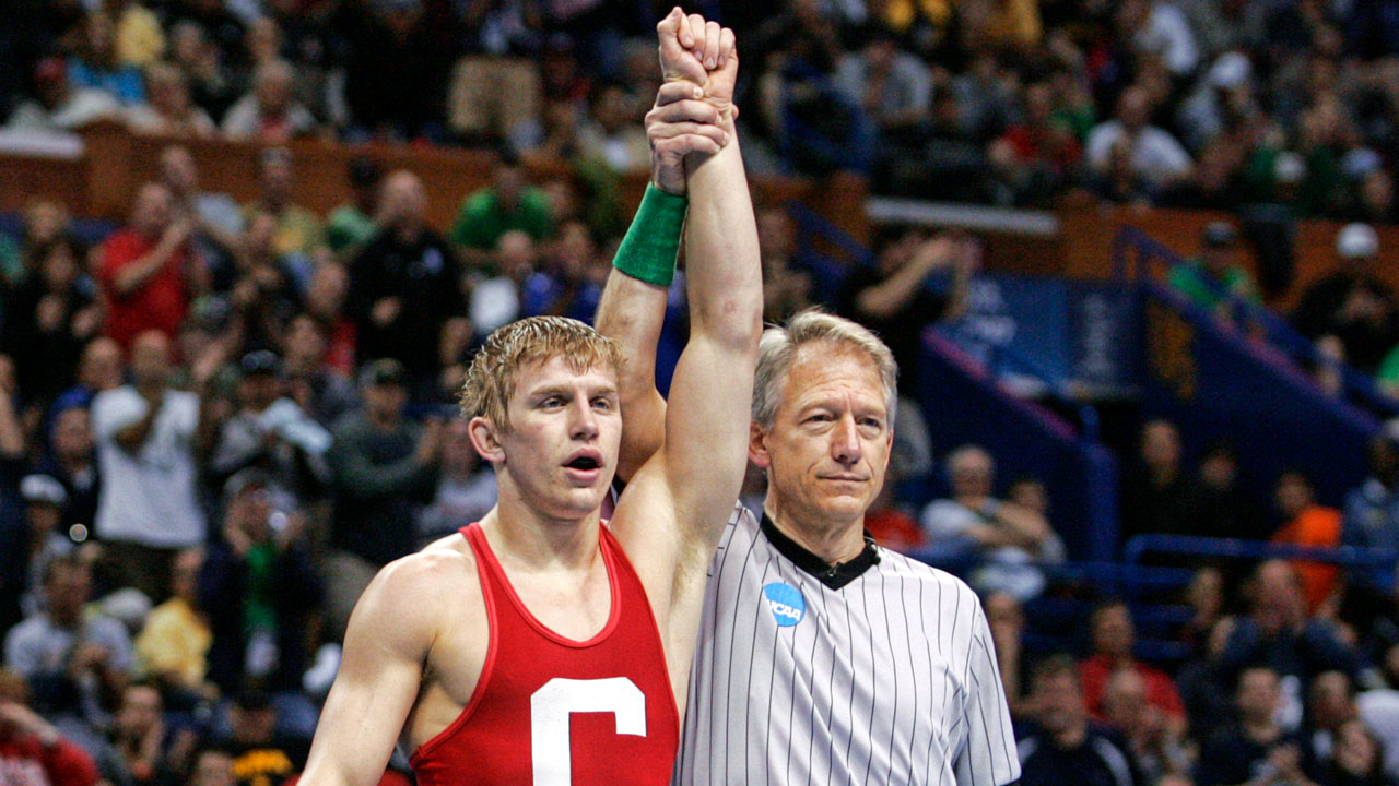 An NCAA referee raises Kyle Dake's hand at end of a wrestling match.