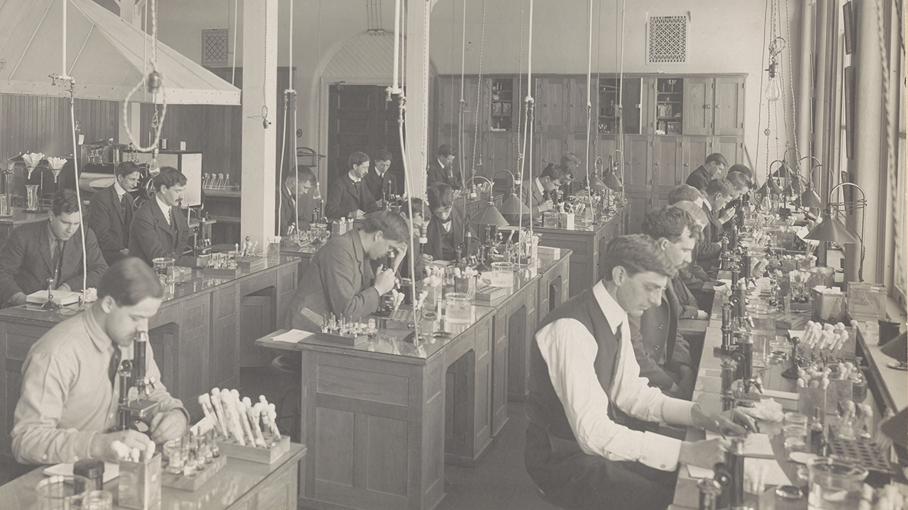 A room full of well-dressed young men working on lab equipment.