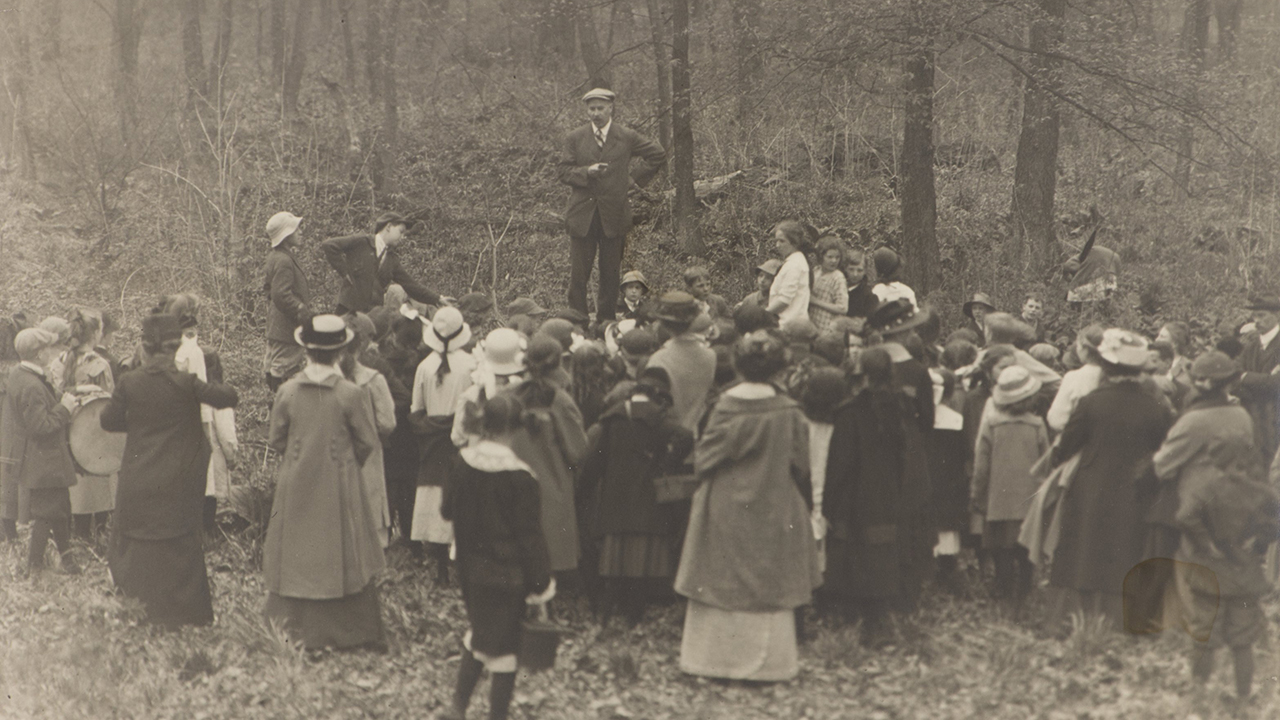 A man stands above a gathered crowd listening to him speak.