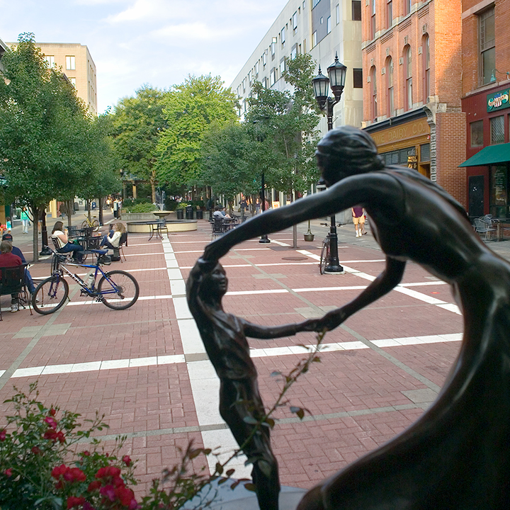 A statue of a dancing mother and child on Ithaca Commons.