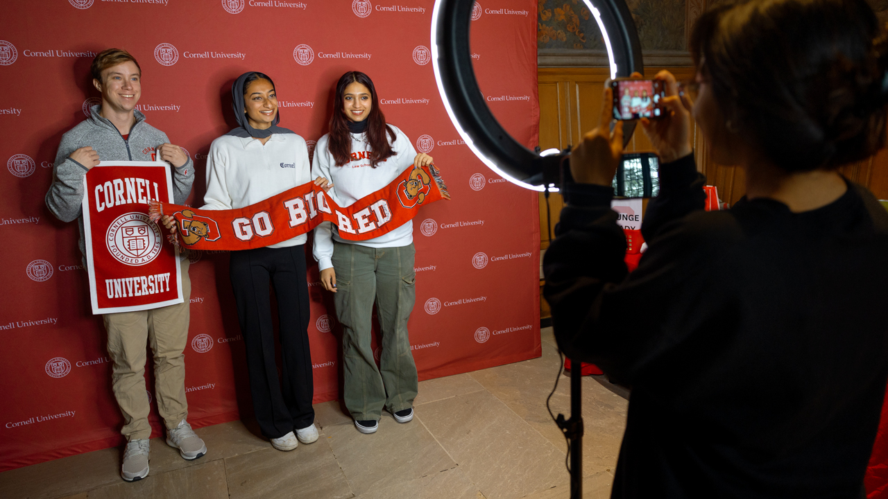 Three students posing for a picture with Cornell swag.