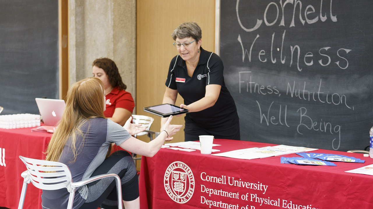 A student at a signup table for Cornell Wellness
