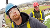 two men in hardhats prepare to install a hawk camera